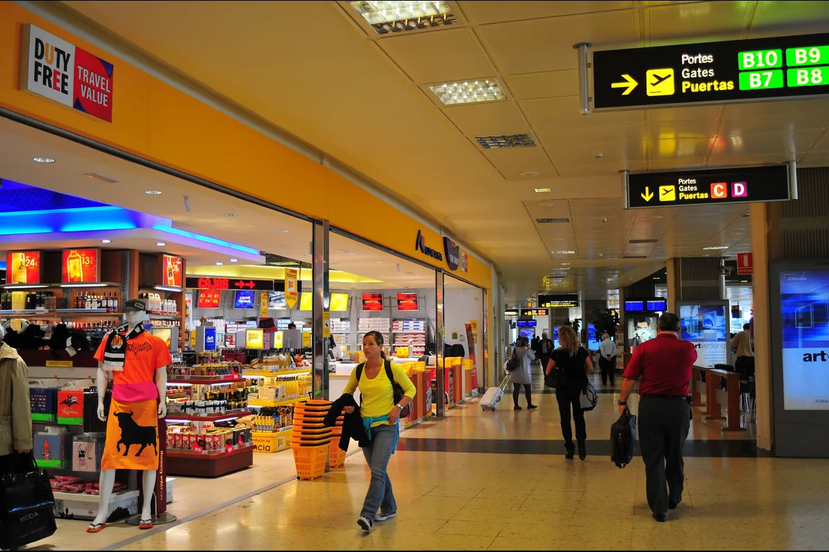 Travellers in an airport terminal beneath a display with gate information